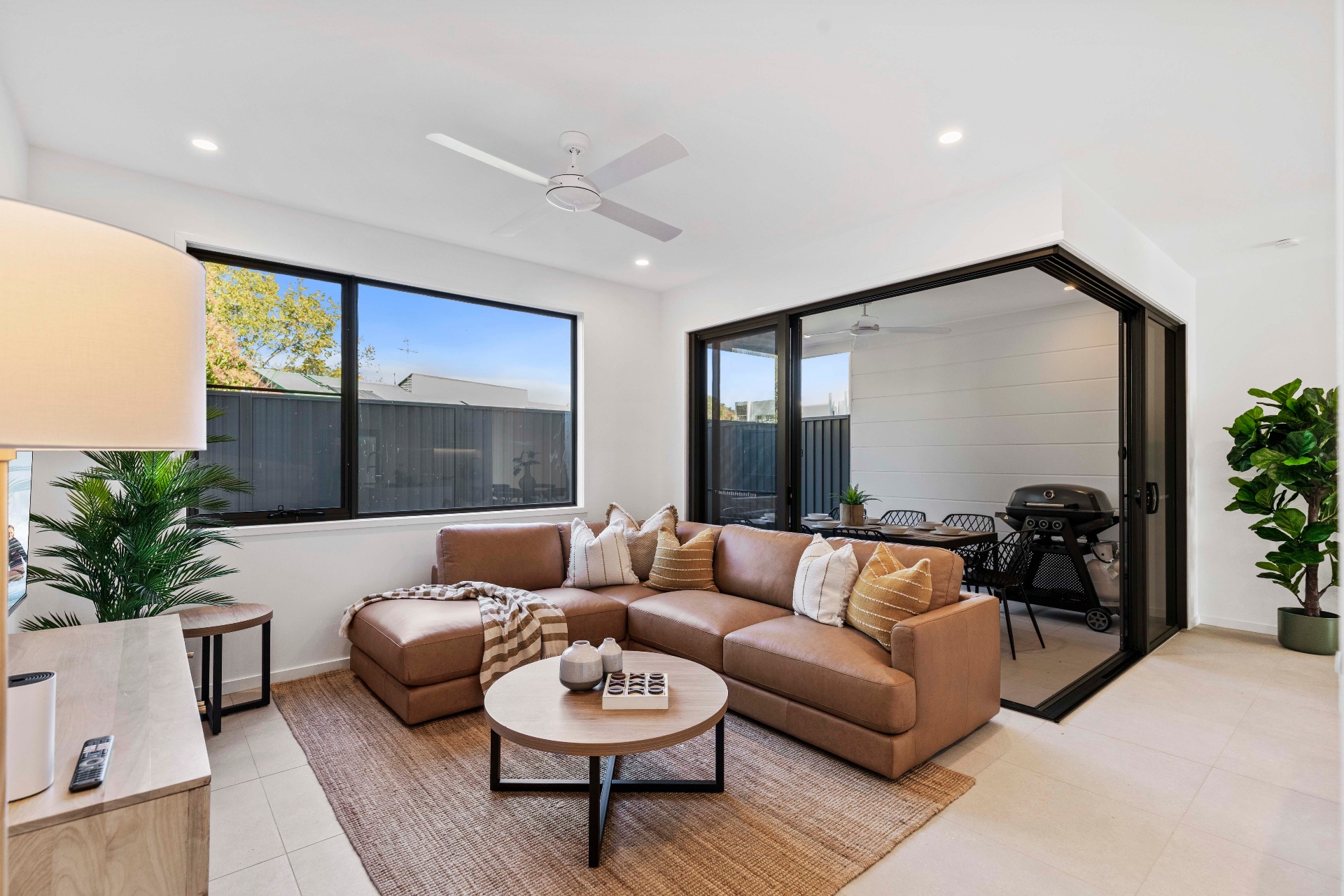 AirBNB — lounge with tan leather sectional opening to alfresco