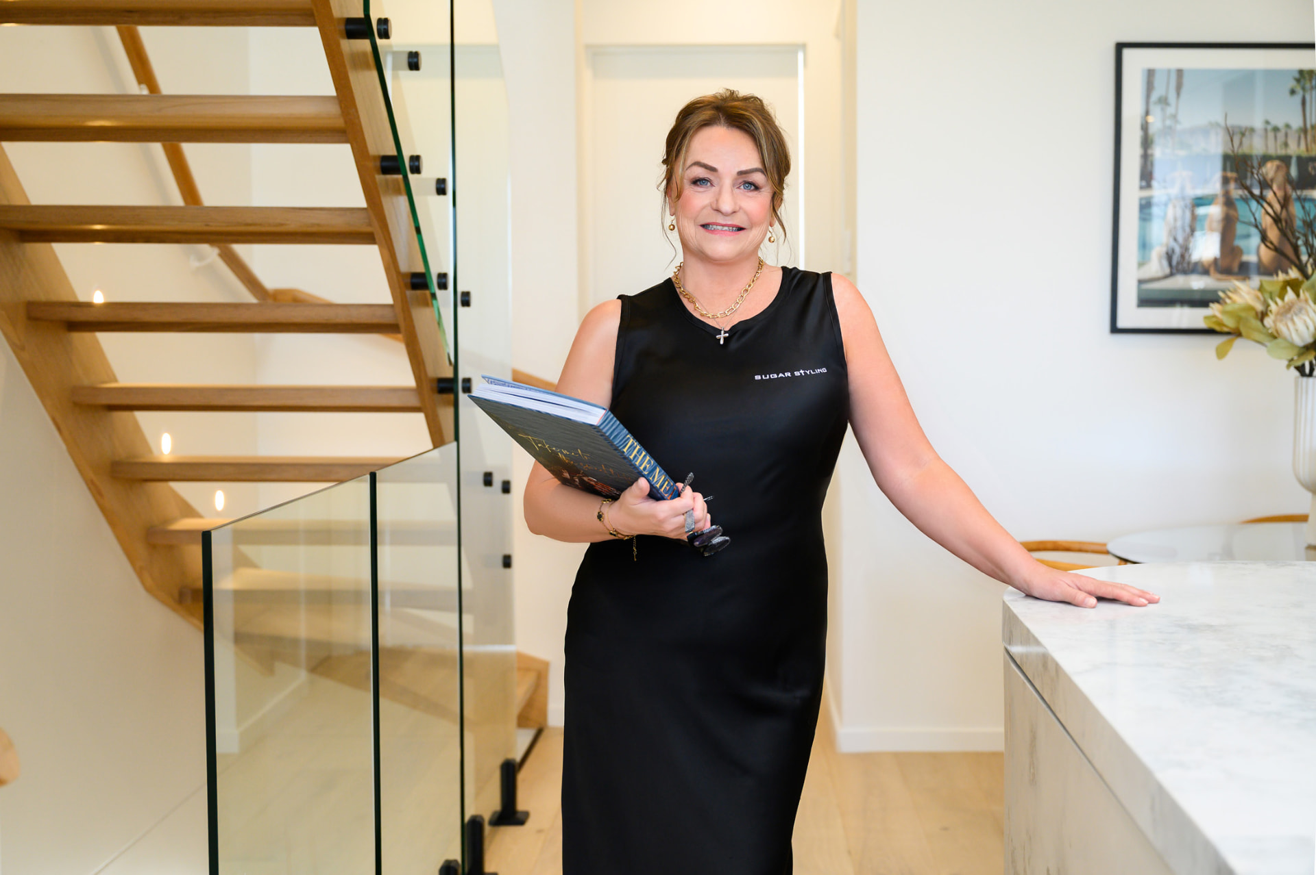 Sherryl from Sugar Styling holding a design book in a styled Gold Coast home