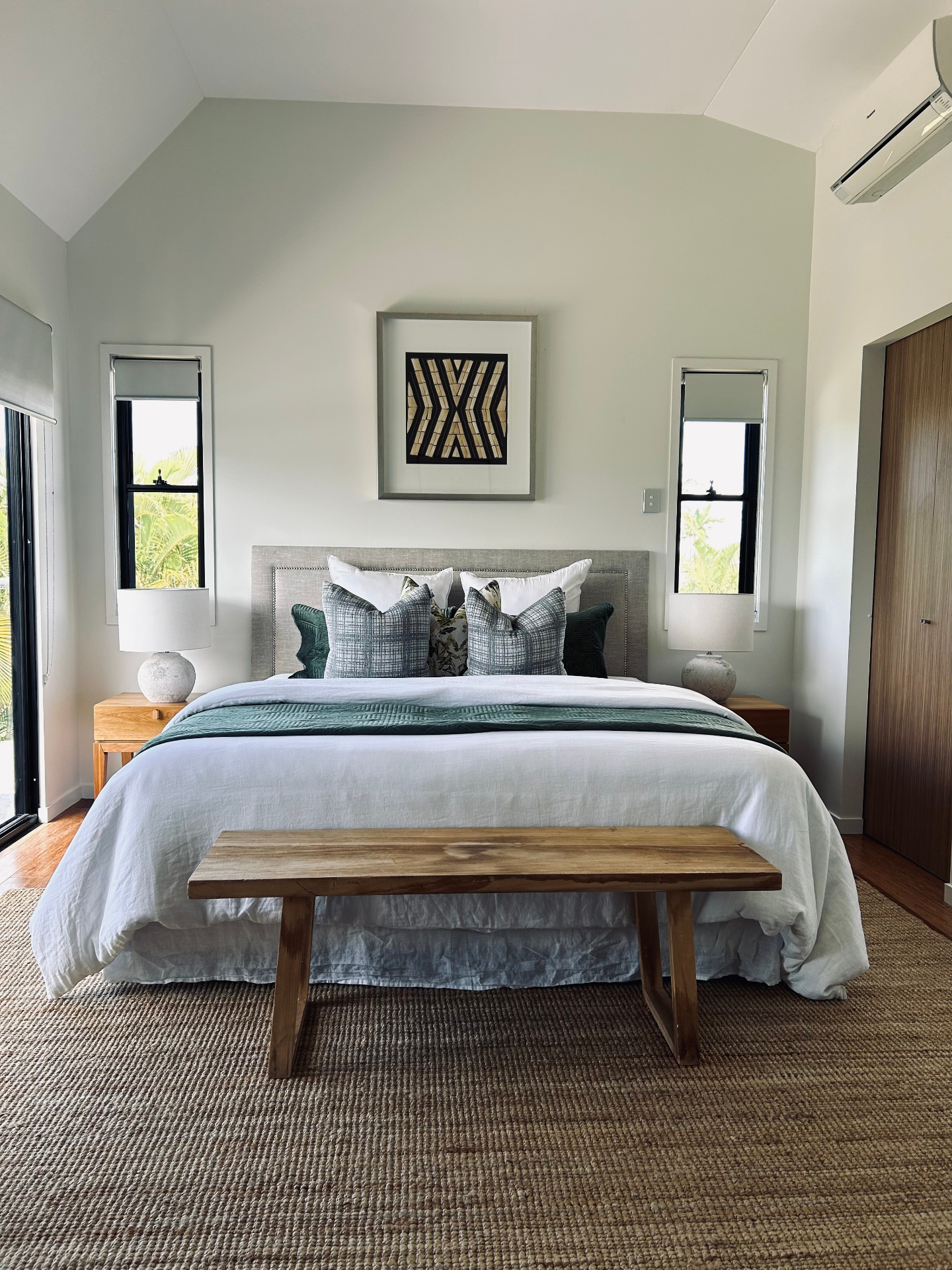 Occupied styling — bedroom with green pillows and timber bench