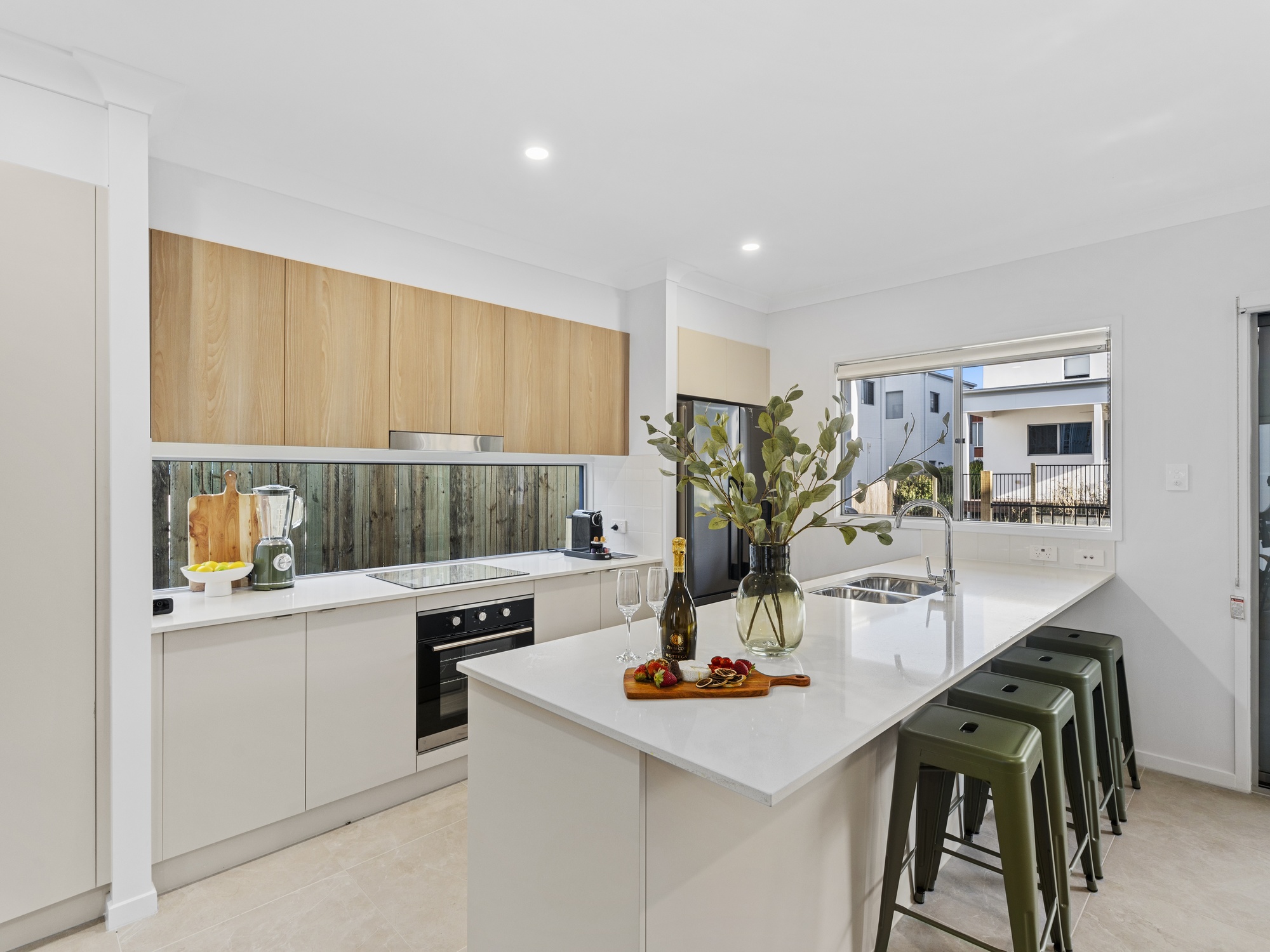 AirBNB — kitchen with timber upper cabinets and green stools