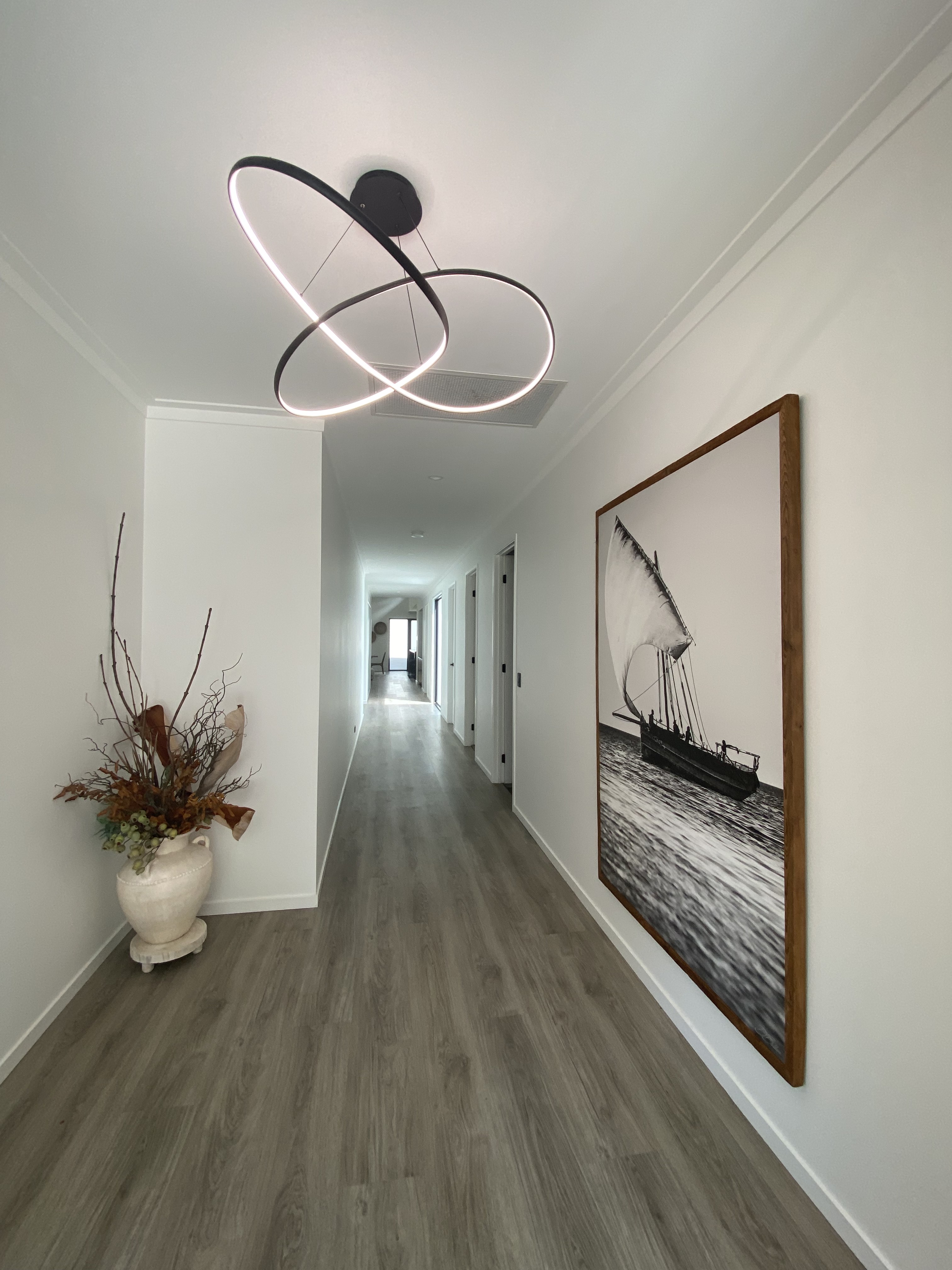 Interior design — hallway with sculptural pendant and sailing art